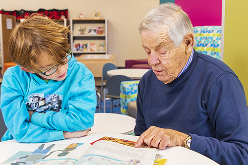 Lou Cohen tutoring a child in the library
